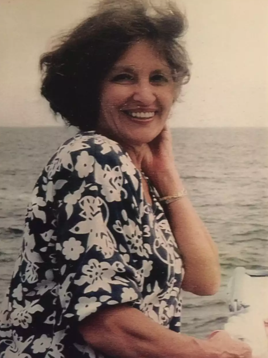 middle aged woman nan on a boat in new england with wild lightly blowing her hair she is smiling with her hand behind her ear and looks very sweet and happy