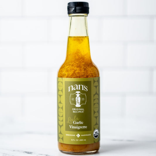 Bottle of nan's Organic Garlic Vinaigrette on a marble surface with a white background