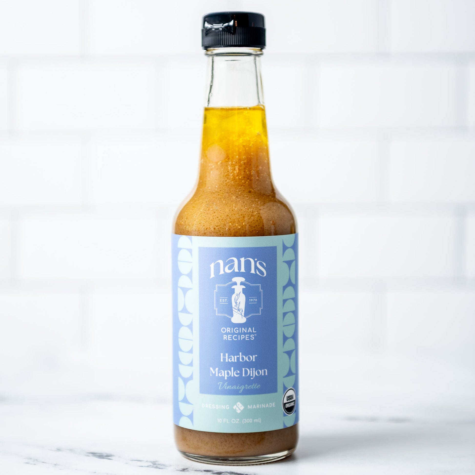 Bottle of Nan's Harber Maple Dijon on a marble surface with a white background