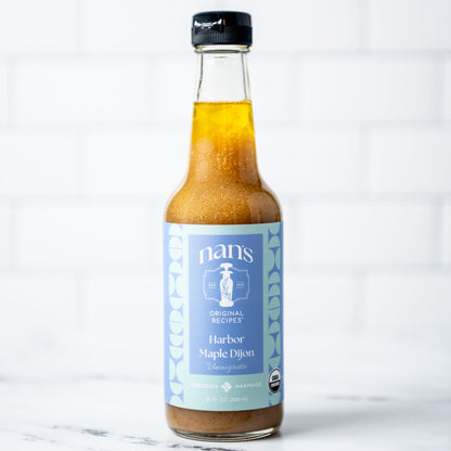 Bottle of Nan's Harber Maple Dijon on a marble surface with a white background