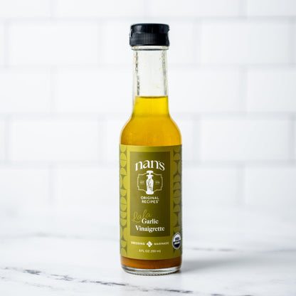 Bottle of Nani's Garlic Vinaigrette on a marble surface with a white background