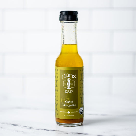 Bottle of Nani's Garlic Vinaigrette on a marble surface with a white background